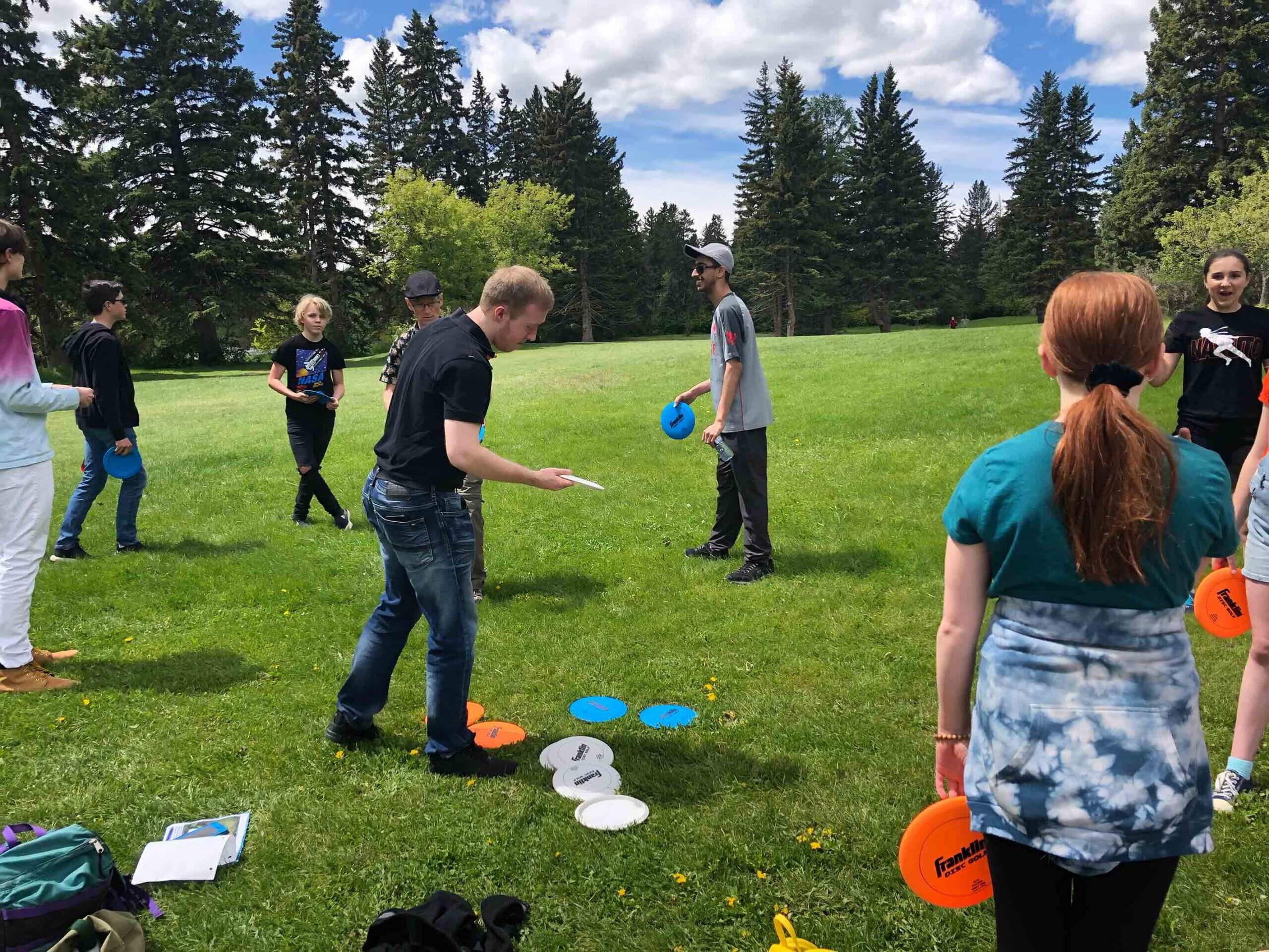 Highschool students play golf disc in a park in Calgary