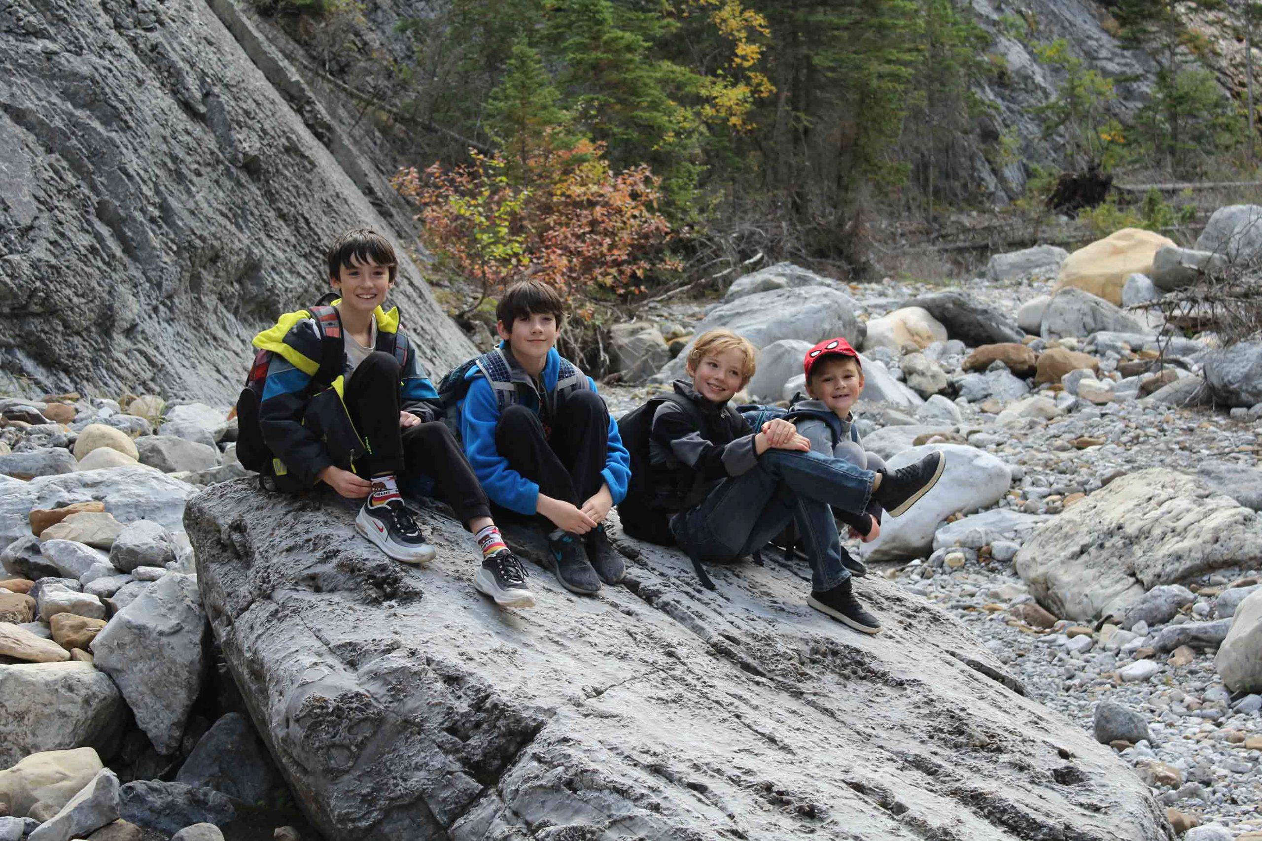 Banbury students take a break sitting on a rock during a hike along heart creek in the rockies